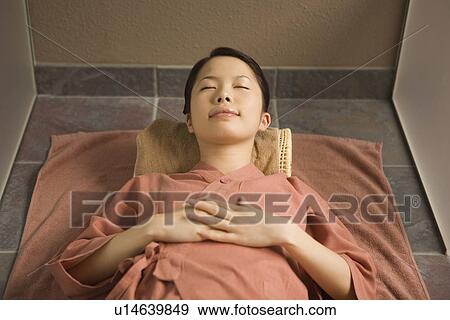 Stock Photo - Young woman lying at bedrock bath. Fotosearch
