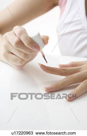 Stock Image - Young woman painting manicure. Fotosearch