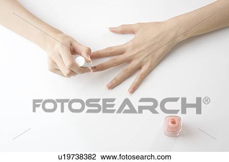 Stock Image - Young woman painting manicure. Fotosearch