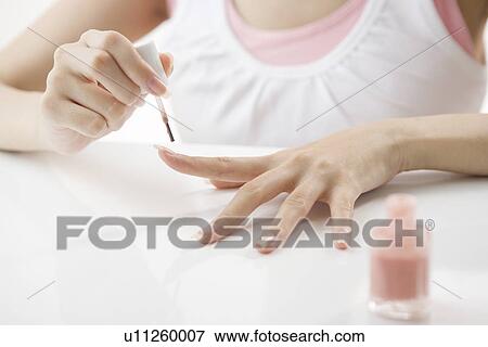 Stock Photo - Young woman painting manicure. Fotosearch