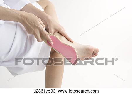 Stock Image - Young woman rubbing foot. Fotosearch