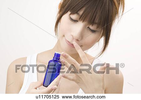 Stock Photography - Young woman smelling aromatherapy bottle. Fotosearch