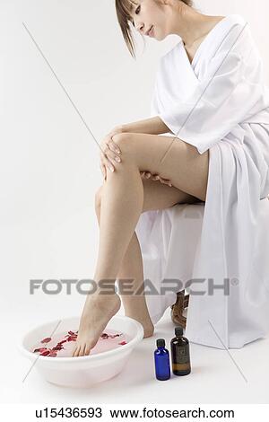 Stock Image - Young woman taking footbath. Fotosearch