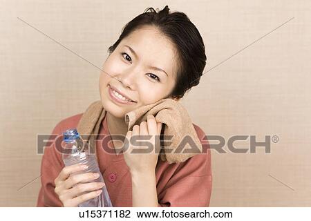 Stock Image - Young woman wiping face with towel. Fotosearch