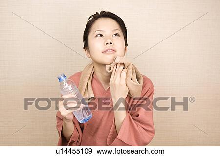 Young woman wiping face with towel View Large Photo Image Stock Photo - Young woman wiping face with towel. Fotosearch