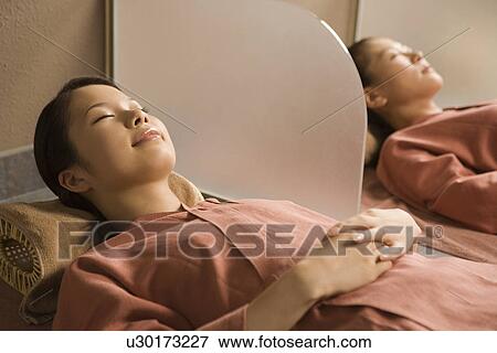 Stock Photo - Young women lying at bedrock bath. Fotosearch