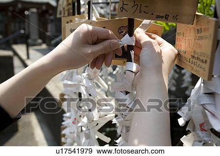 Stock Photo - Hands of a woman tying fortune paper. Fotosearch