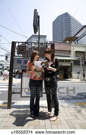 Picture - Two women looking at guidebook. Fotosearch