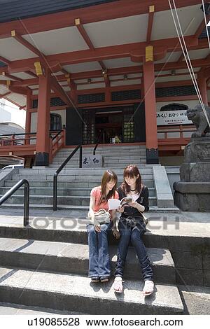 Stock Photo - Two women looking at guidebook. Fotosearch