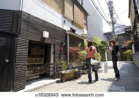 Two women standing in narrow street View Large Photo Image Stock Image - Two women standing in narrow street. Fotosearch