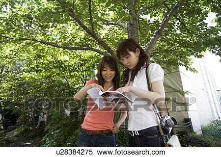 Stock Photography - Two young women looking at guidebook. Fotosearch