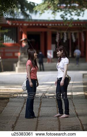 Stock Image - Two young women standing at shrine. Fotosearch