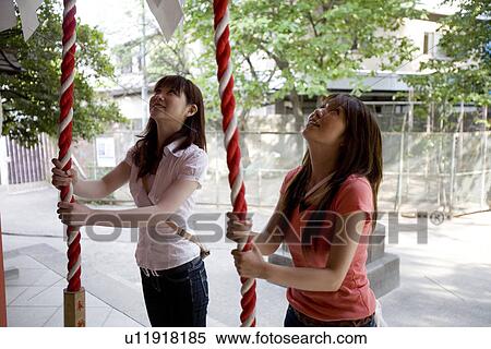 Stock Photography - Two young women standing at shrine. Fotosearch