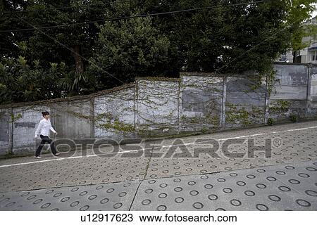 Stock Image - Young woman walking up slope. Fotosearch