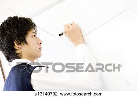 Stock Image - Teenage boy writing on white board. Fotosearch