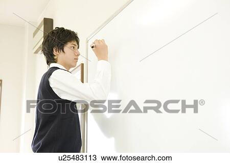 Stock Image - Teenage boy writing on white board. Fotosearch