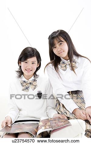Stock Image - Teenage girls reading book. Fotosearch