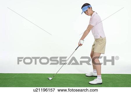 Stock Photo - Female golfer preparing to hit golf ball. Fotosearch