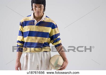 Stock Photograph - Rugby player holding ball. Fotosearch