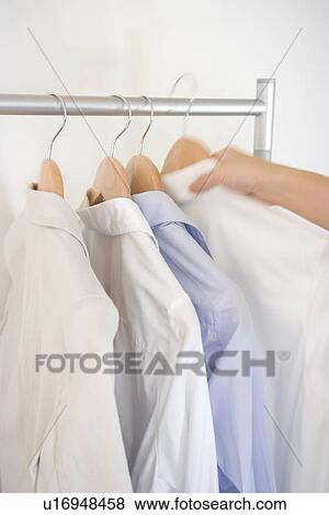 Stock Photo - Woman picking shirt on hanger. Fotosearch