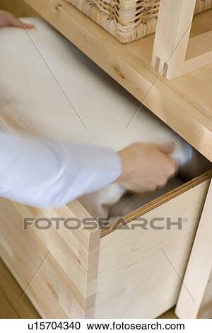 Stock Image - Woman putting blanket in drawer. Fotosearch