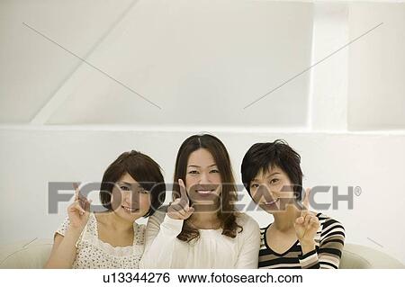 Stock Photograph - Portrait of three young women pointing. Fotosearch