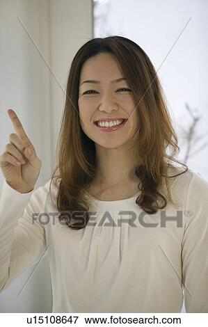 Stock Photo - Portrait of young woman pointing. Fotosearch
