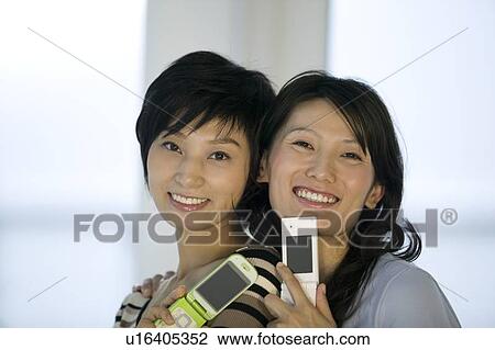 Stock Image - Two women holding mobile phones. Fotosearch