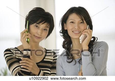 Two women using mobile phones View Large Photo Image Stock Image - Two women using mobile phones. Fotosearch