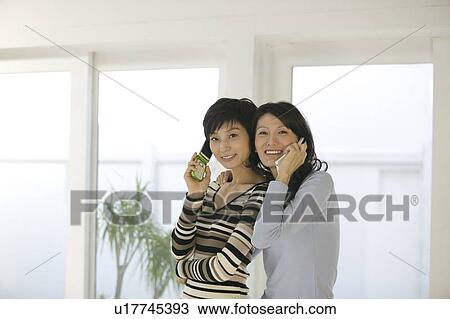 Two women using mobile phones View Large Photo Image Stock Image - Two women using mobile phones. Fotosearch