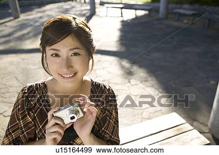 Stock Photo - Young woman holding digital camera. Fotosearch