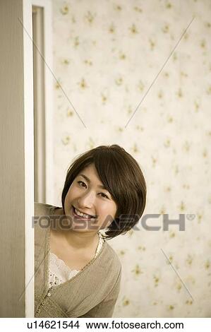 Picture - Young woman opening door. Fotosearch