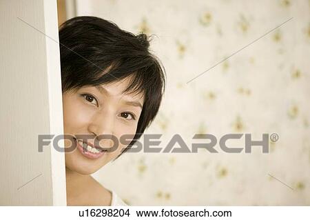 Picture - Young woman opening door. Fotosearch