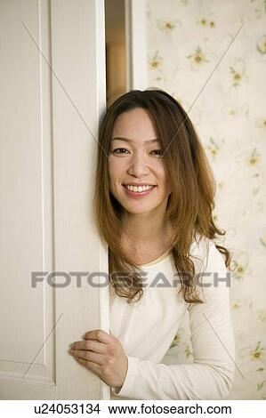 Picture - Young woman opening door. Fotosearch