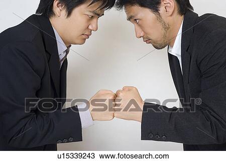 Stock Image - Two businessmen glaring each other. Fotosearch