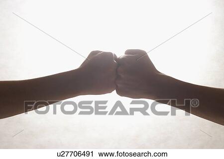 Stock Image - Two hands touching knuckles together . Fotosearch