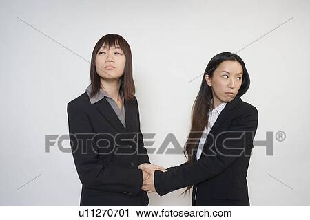 Stock Image - Two young businesswomen shaking hands. Fotosearch