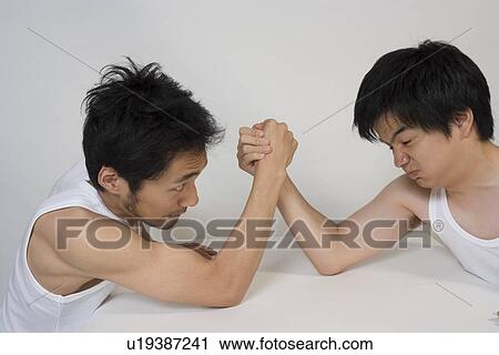 Stock Image - Two young men arm wrestling. Fotosearch