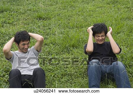 Stock Image - Two young men doing sit-ups. Fotosearch