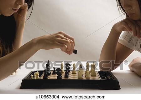 Picture - Two young women playing chess. Fotosearch