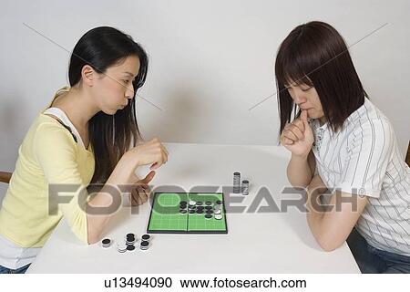 Two young women playing Othello game View Large Photo Image Stock Image - Two young women playing Othello game. Fotosearch