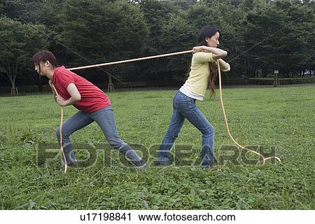 Stock Image - Two young women pulling rope. Fotosearch