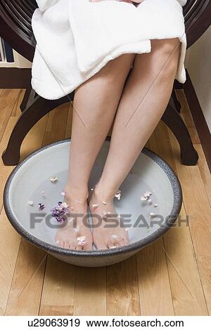 Stock Photo - Young woman putting her legs in footbath. Fotosearch