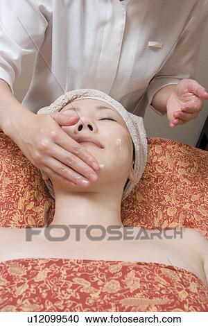 Stock Image - Young woman receiving facial massage. Fotosearch