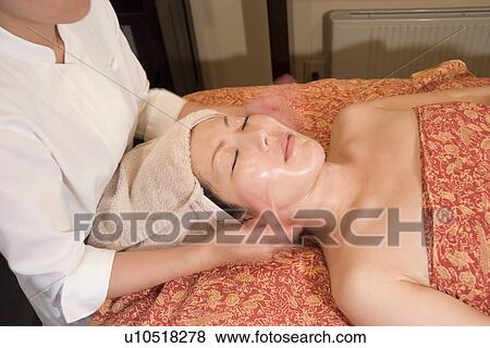 Stock Photo - Young woman receiving facial massage. Fotosearch