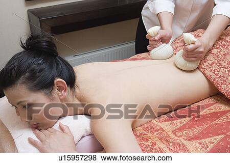 Stock Photo - Young woman receiving herbal ball massage. Fotosearch