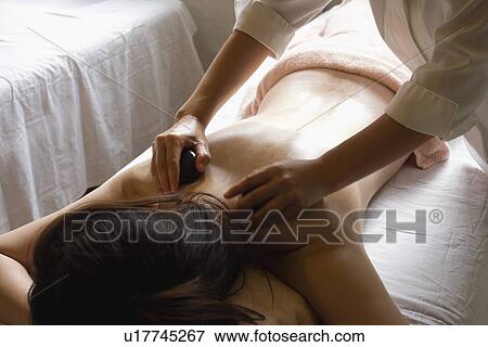 Stock Photo - Young woman receiving stone massage. Fotosearch