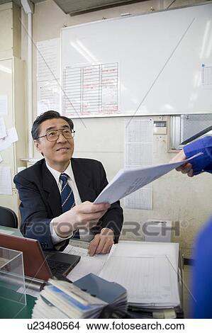 Picture - Mature businessman receiving document. Fotosearch