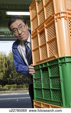 Stock Photo - Mature man carrying plastic boxes. Fotosearch