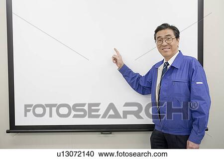Stock Image - Mature man pointing whiteboard. Fotosearch